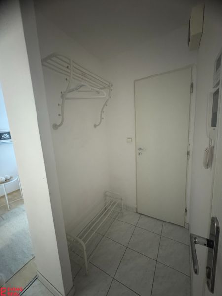 Előszoba fogassal és cipősszekrénnyel az egyszobás lakásban, padlócsempével.