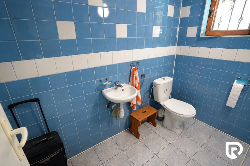 Fürdőszoba egy családi házban kék csempékkel, mosdóval és WC-vel.