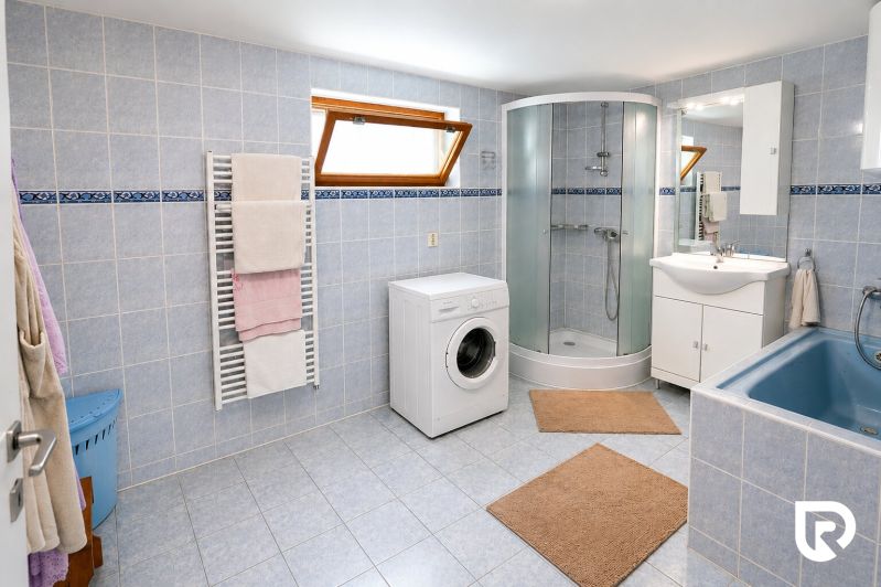 Fürdőszoba családi házban káddal, zuhanyzóval és mosógéppel.