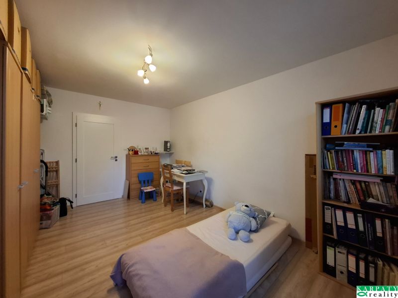 Szoba íróasztallal, ággyal és fa dekorációjú padlóval egy háromszobás lakásban.