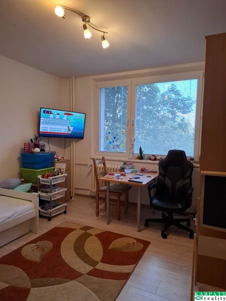 Gyerekszoba ággyal, asztallal és fa dekorációjú padlóval egy háromszobás lakásban.
