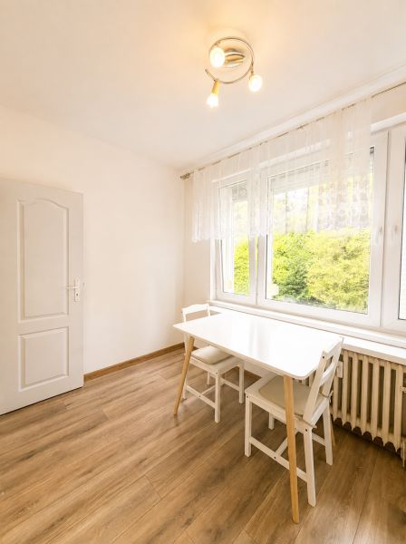 Étkező sarok fehér asztallal és székekkel, fa dekor padló, 3 szobás lakás.
