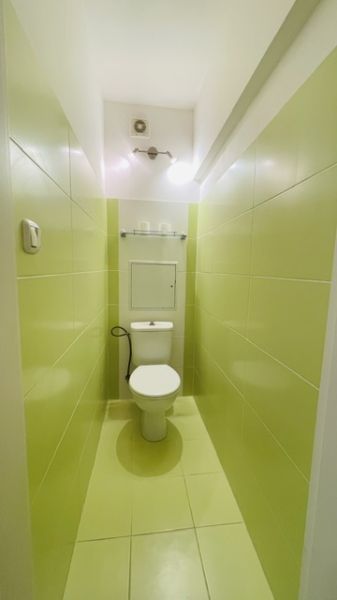 Keskeny fürdőszoba világoszöld csempékkel és WC-vel egy háromszobás lakásban.