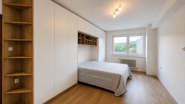 Hálószoba egy háromszobás lakásban, ággyal, beépített szekrényekkel és fa dekorációjú padlóval.