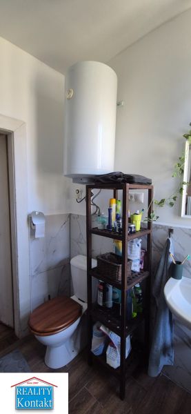 A 2 szobás lakás fürdőszobája WC-t, polcos állványt és mosdókagylót tartalmaz.