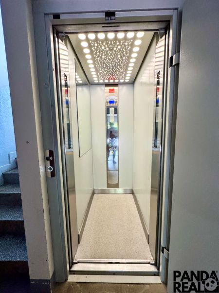 Lift világított mennyezettel és világos falakkal egy lakóházban.
