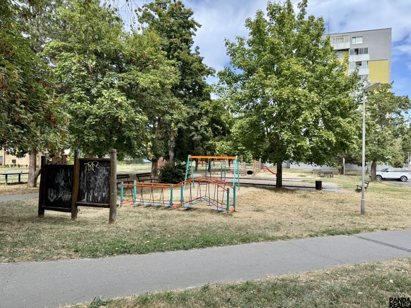 Játszótér fákkal körülvéve a Topoľčany város parkjában, közel egy egyszobás lakáshoz.