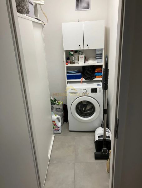 Mosókonyha mosógéppel és tárolószekrényekkel egy háromszobás lakásban.