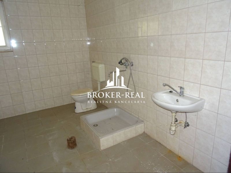 Fürdőszoba raktárakban és csarnokokban csempével, zuhanyzóval és WC-vel.