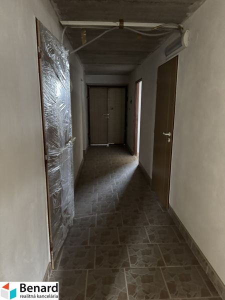 Folyosó egy családi házban, bézs burkolattal a padlón és műanyag ajtókkal.