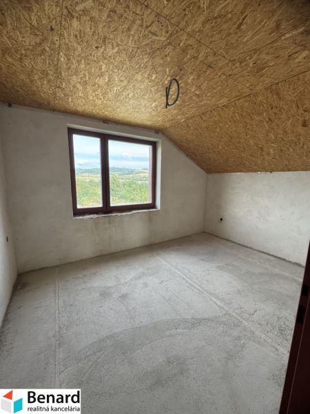 Kilátás egy családi ház üres szobájába tetőablakkal és betonpadlóval.