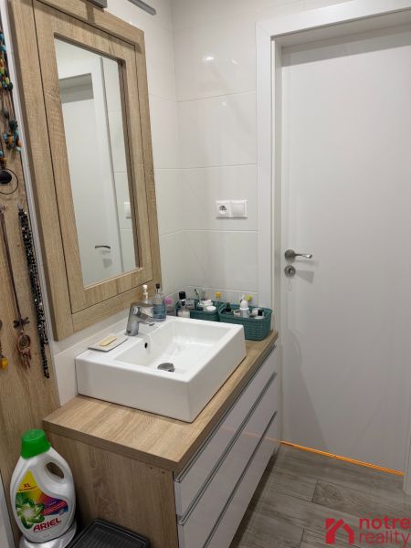 Fürdőszoba egy kétszobás lakásban mosdóval és fa dekorációjú bútorokkal.