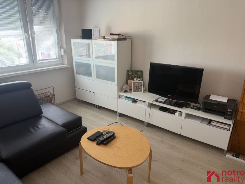 Nappali egy kétszobás lakásban fa dekoros padlóval és modern bútorokkal.