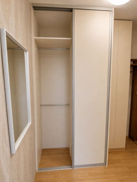 Beépített szekrény tolóajtókkal és fa dekorációjú padlóval egy kétszobás lakásban.