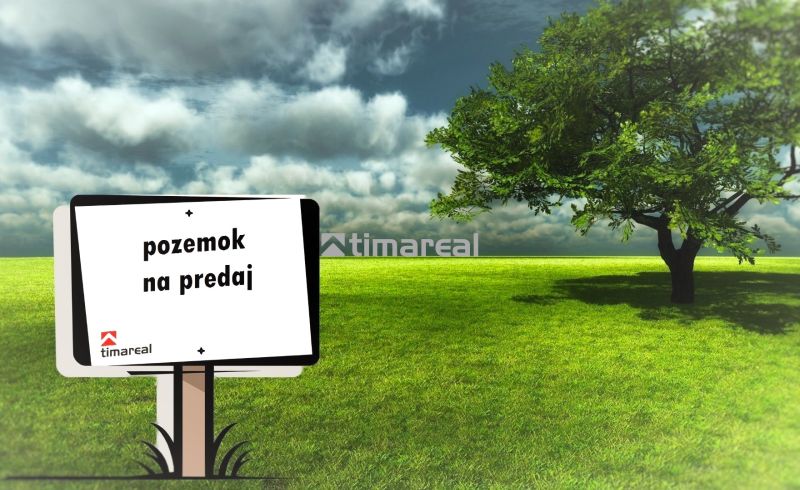 A tábla földterület eladását hirdeti, egy zöld gyep látható a fa mellett.