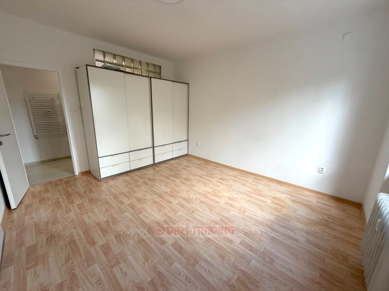 Szoba egy kétszobás lakásban, fa dekorációjú padlóval és nagy ruhásszekrénnyel.