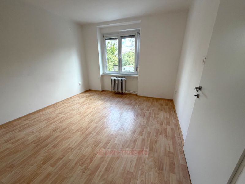Szoba egy kétszobás lakásban fa dekorációs padlóval és nagy ablakkal.