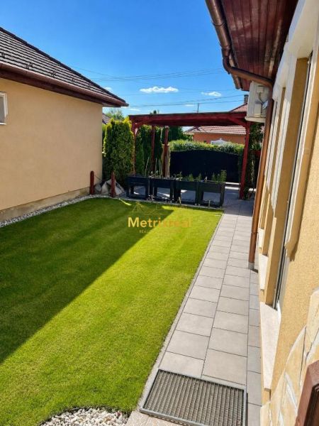 A családi ház kertje Darnózseliben zöld gyepes és kövezett sétányos.