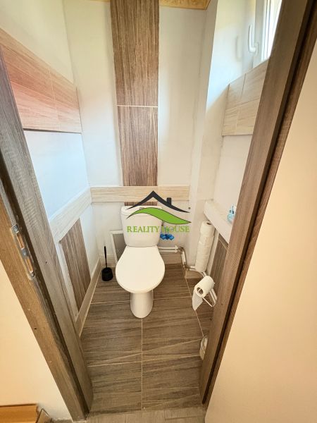 WC egy családi házban kerámia padlóval és keskeny ablakkal.
