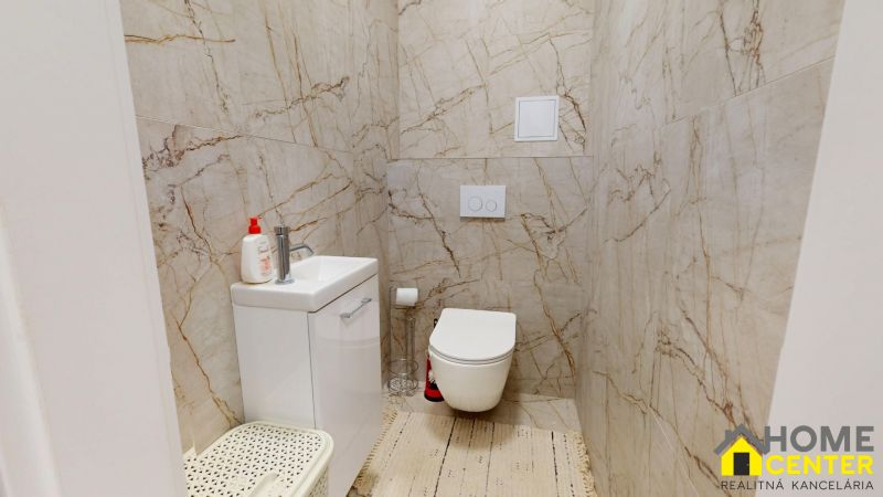 Fürdőszoba kétszobás lakásban WC-vel, mosdóval és márványburkolattal a falakon.