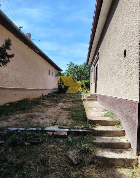 Családi ház Tardoskedden udvarral, ahol lépcső vezet a két épület között.