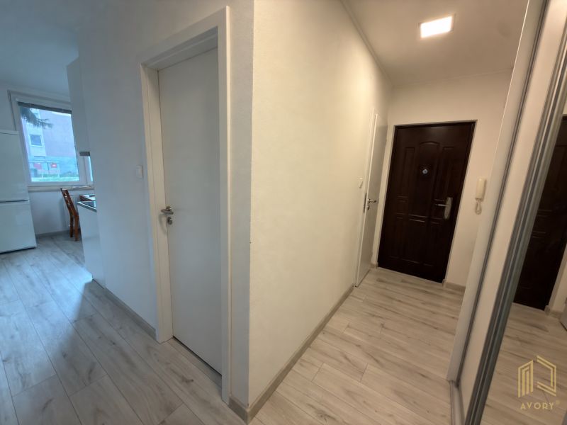 Világos folyosó egy kétszobás lakásban, fa mintázatú padlóval.