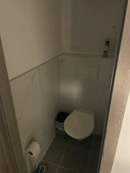 Csempeburkolatú és légfrissítővel ellátott WC egy kétszobás lakásban.