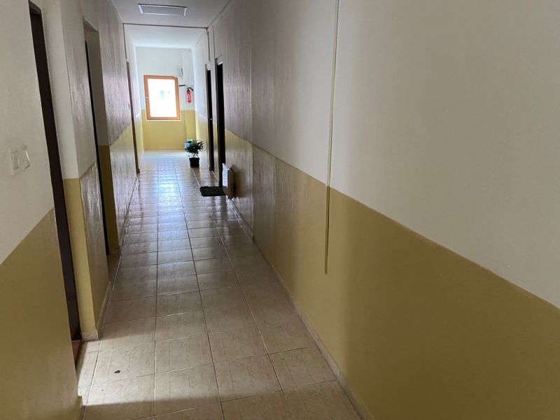 Folyosó irodákban csempével és szobanövénnyel az ablak mellett.