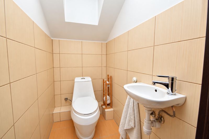 Fürdőszoba családi házban WC-vel és mosdóval, bézs csempék.