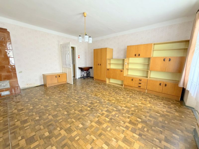 Nappali fa mintázatú padlóval, világos bútorokkal és kandallóval egy családi házban.