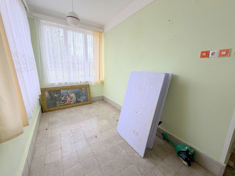 Családi ház belső tere festménnyel, fehér függönyös ablakokkal és zöld falakkal.