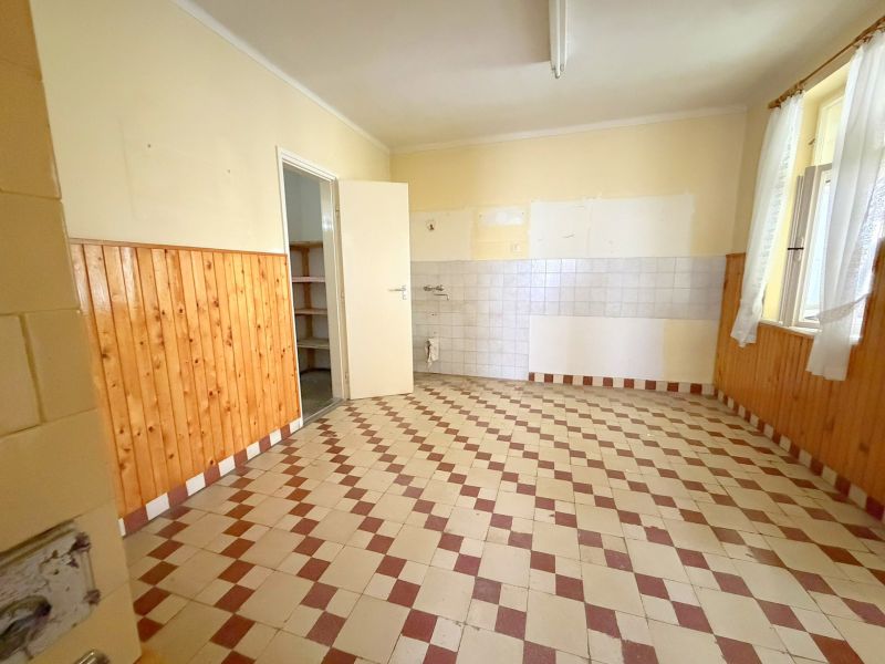 Családi ház konyhája csempével és fa burkolattal a falakon.