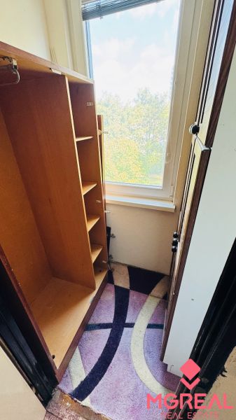Háromszobás lakás gardróbja nagy ablakos kilátással és színes szőnyeggel.
