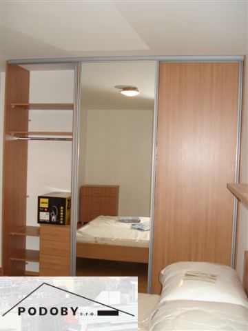 Hálószoba fa mintás padlóval és beépített szekrénnyel egy háromszobás lakásban.