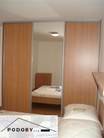 Hálószoba egy háromszobás lakásban nagy beépített szekrénnyel és fa dekorációjú padlóval.