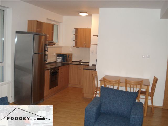 Konyha egy háromszobás lakásban konyhabútorral, étkezőasztallal és fa dekorációjú padlóval.