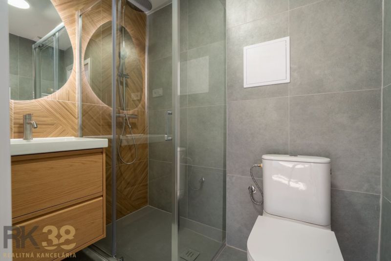 Fürdőszoba zuhanyzóval, mosdóval és WC-vel egy egyszobás lakásban.