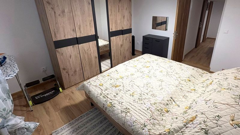 Hálószoba ággyal, szekrénnyel és fa dekorációjú padlóval egy családi házban.