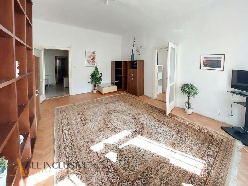 Világos nappali fa dekor padlóval, szőnyeggel és bútorokkal egy kétszobás lakásban.