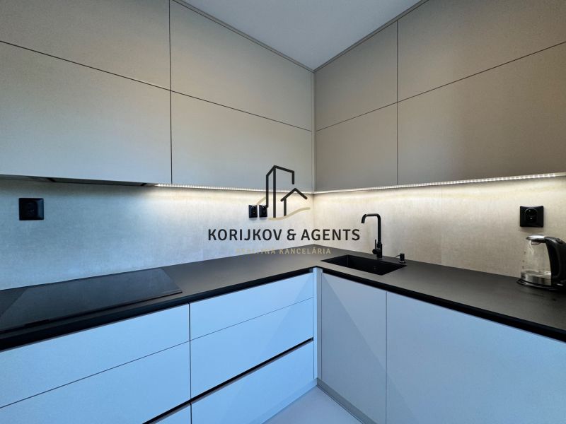 Egy háromszobás lakás konyhája modern szekrényekkel és LED világítással.