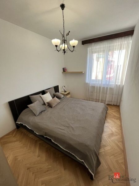 Hálószoba franciaággyal és fa dekorációjú padlóval egy háromszobás lakásban.