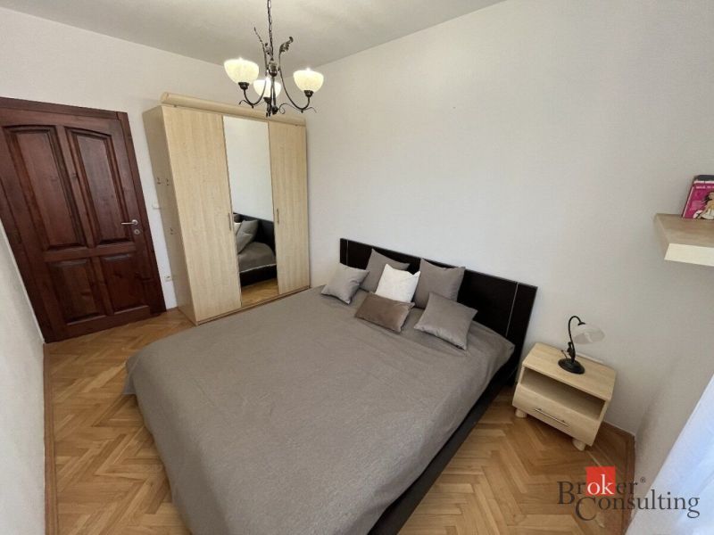 Hálószoba egy háromszobás lakásban franciaággyal és szekrénnyel, fa dekorációjú padlóval.