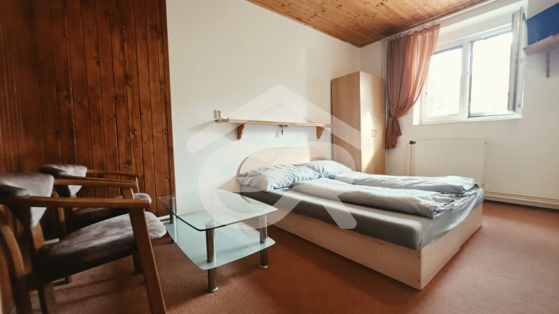 Nyaraló apartman hálószobája franciaággyal, székekkel és ablakkal, fa dekorációjú padlóval.