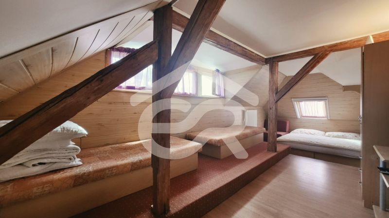 Tetőtéri szoba egy üdülő apartmanban fa dekorációjú padlóval és ágyakkal.