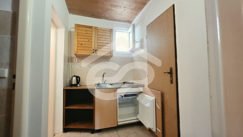 Konyhasarok a nyaraló apartmanban fa szekrényekkel, mosogatóval és minibárral.