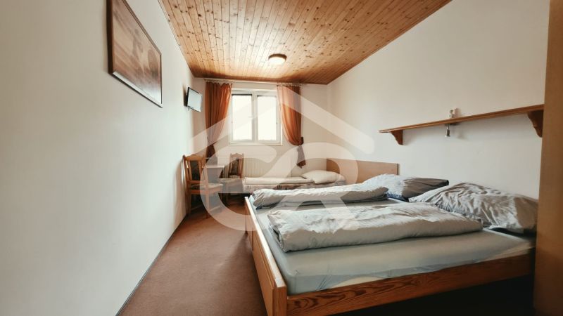 Hálószoba üdülő apartmanban két ággyal és TV-vel, fa dekoros padlóval.