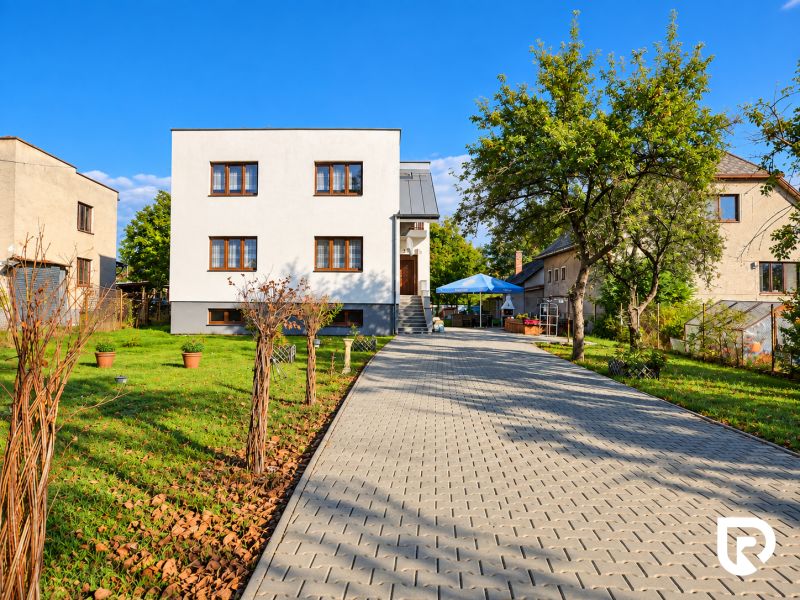 Családi ház Martinban, bejárati úttal és kerttel, zölddel és fákkal körülvéve.