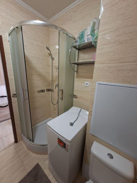 Zuhanykabin mosógéppel és WC-vel a garzonlakásban.