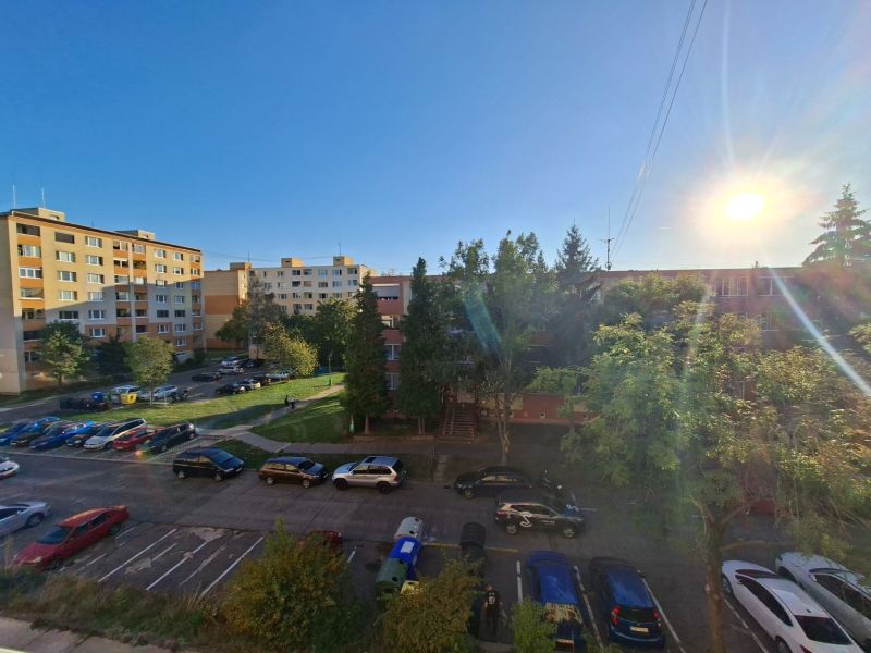 Autók parkolnak a Benedikta utcában Prievidzánál a garzonlakás mellett, napos nap.