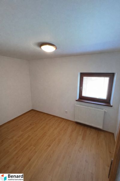 Szoba egy családi házban fa dekorációjú padlóval és ablakkal, radiátorral.